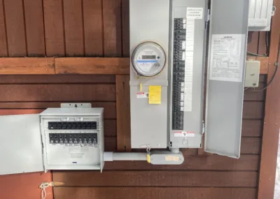 Electrical utility setup with meters and circuit breaker panels mounted on a wooden wall.