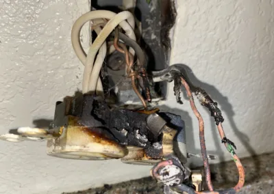 Damaged and burned electrical outlet with exposed wiring.